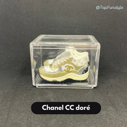 Mini sneakers Chanel CC doré en vitrine transparente - paire 3D métallique or et crème