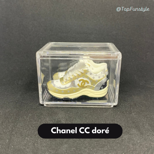 Mini sneakers Chanel CC doré en vitrine transparente - paire 3D métallique or et crème
