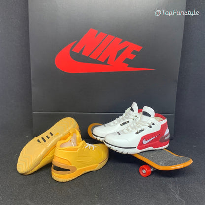 Mini sneakers LeBron 1 Wheat jaune blé, semelle visible, et First Game blanc et rouge sur un mini skateboard