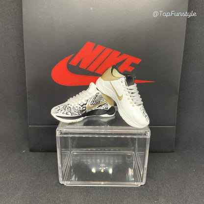 Mini sneakers Kobe 5 Big Stage Parade sur la vitrine : un pied à motifs graphiques noir et blanc, l’autre plus épuré
