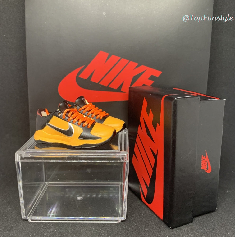Mini sneakers Kobe 5 Bruce Lee jaune et noir posées sur la vitrine, boîte miniature à côté