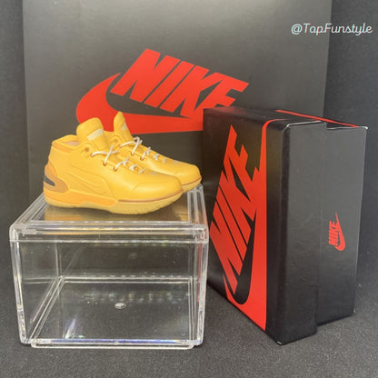 Mini sneakers LeBron 1 Wheat jaune blé sur la vitrine, boîte miniature posée à côté
