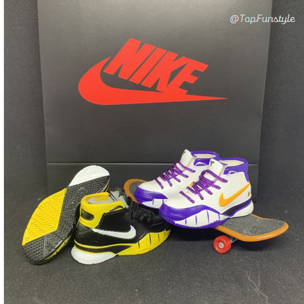 Mini sneakers Kobe 81 Points blanc et violet sur un mini skateboard, à côté du coloris Kobe 1 Del Sol